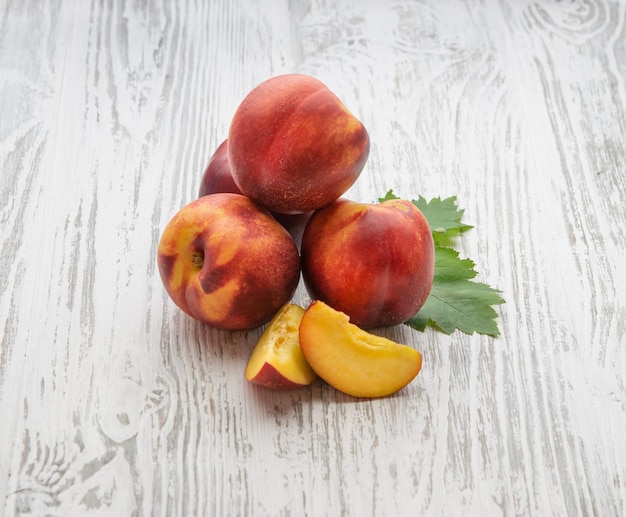 Nectarina fresca com folhas em um fundo branco de madeira Fazenda de frutas saudáveis e ecologicamente corretas Estilo rústico