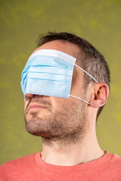 Negador pandémico con una máscara azul quirúrgica anticovid que cubre sus ojos