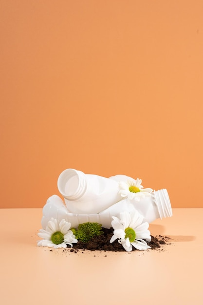 Negative Auswirkungen auf die Natur Plastikflaschen zerquetschen schöne Blumen, die im Boden wachsen Bodenverschmutzung Die Idee der Plastikverschmutzung Das Konzept der Umweltschädigung Kreative Komposition