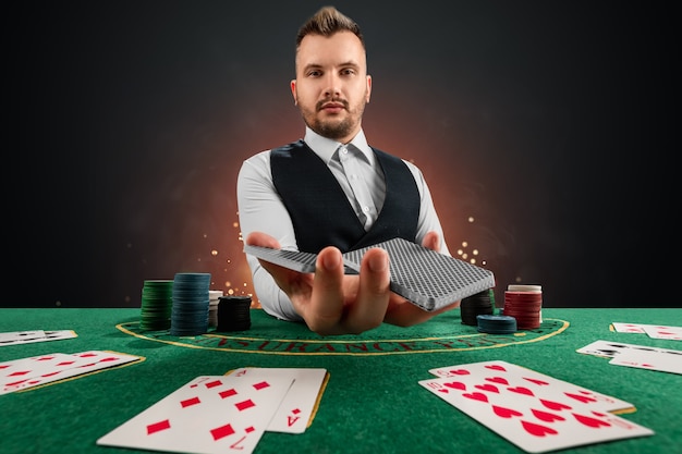 Negociante masculino no casino à mesa. conceito de cassino, jogos de azar, pôquer, fichas na mesa verde do cassino.