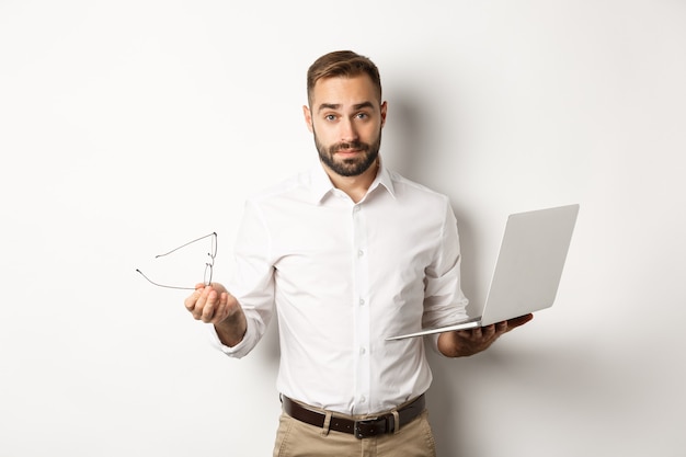 Negocio. Apuesto hombre de negocios que parece confundido después de trabajar con la computadora portátil, contra el fondo blanco. Copia espacio