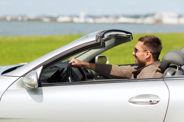 negócio automotivo, transporte, lazer e conceito de pessoas - homem feliz dirigindo carro conversível ao ar livre