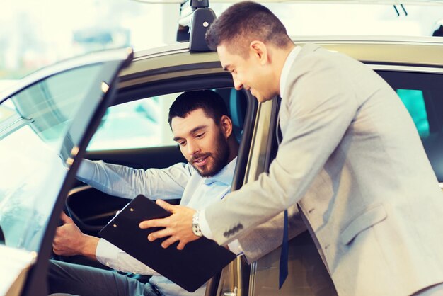 negocio de automóviles, venta de automóviles, consumismo y concepto de personas - hombre feliz con concesionario de automóviles en exhibición de automóviles o salón