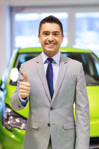 Foto negocio de autos, venta de autos, consumismo, gesto y concepto de personas - hombre feliz mostrando su aprobación en el auto show o salón