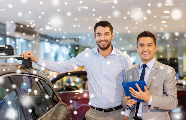 negocio de autos, venta de autos, tecnología y concepto de personas - hombre feliz y concesionario de autos con computadora de tablet pc en auto show o salón sobre efecto de nieve