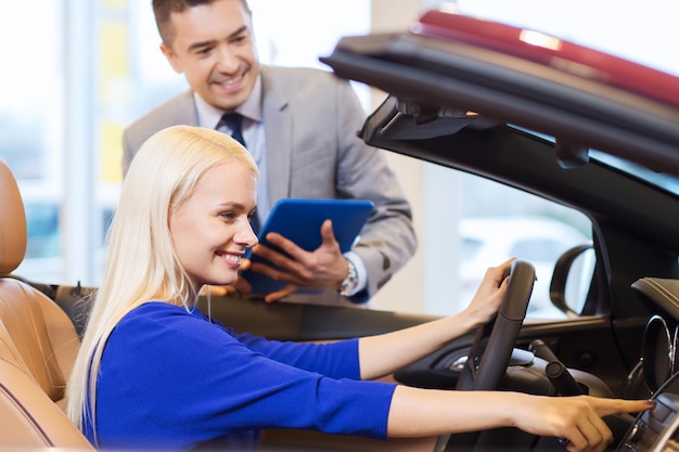 negocio de autos, venta de autos, tecnología y concepto de personas - mujer feliz y concesionario de autos con computadora de tablet pc en auto show o salón