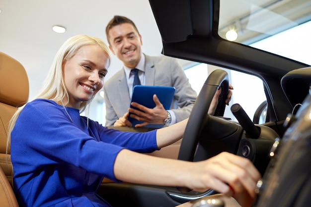 negocio de autos, venta de autos, tecnología y concepto de personas - mujer feliz y concesionario de autos con computadora de tablet pc en auto show o salón