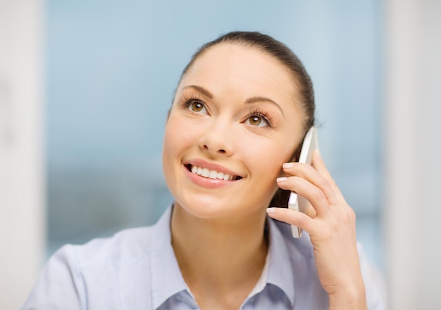 negocio y concepto de comunicación - mujer de negocios africana sonriente con teléfono inteligente en la oficina