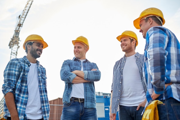 negocio, construcción, trabajo en equipo y concepto de personas - grupo de constructores sonrientes en cascos en el sitio de construcción