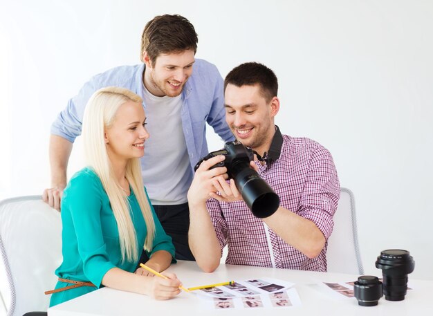 negocio, educación, oficina y concepto de puesta en marcha - equipo creativo sonriente con cámara fotográfica trabajando en la oficina