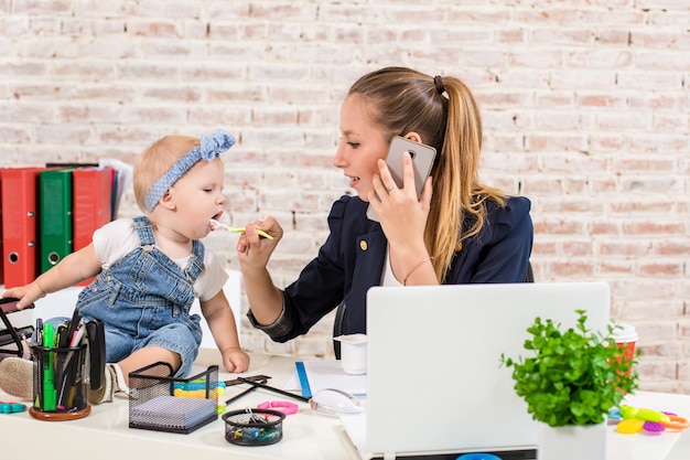 Negócio familiar - telecomutação Mulher de negócios e mãe com criança fazendo uma ligação