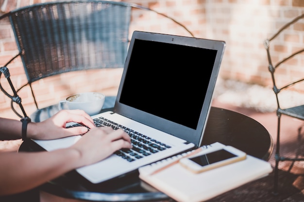 Negócio feminino trabalhando com a imagem de maquete de laptop com tela preta em branco café e sma