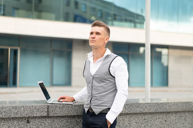 Negocio. Hombre de negocios usando la computadora portátil al aire libre. Serio, pensativo, caucásico, macho, persona de negocios, computadora, exterior, moderno, tecnología, concepto, adulto joven, gerente, crisis, pensamiento, problema, idea