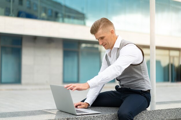 Negocio. Hombre de negocios usando la computadora portátil al aire libre. Serio, pensativo, caucásico, macho, persona de negocios, computadora, exterior, moderno, tecnología, concepto, adulto joven, gerente, crisis, pensamiento, problema, idea