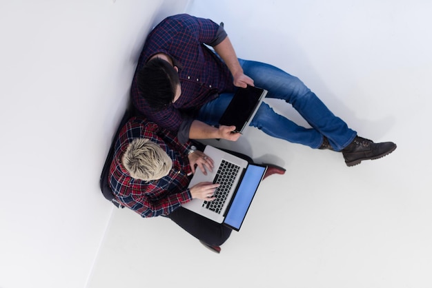 negocio de inicio y nuevo concepto de tecnología móvil con una pareja joven en un interior de oficina moderno y luminoso que trabaja en una computadora portátil y una tableta en un nuevo proyecto creativo y lluvia de ideas, vista superior aérea