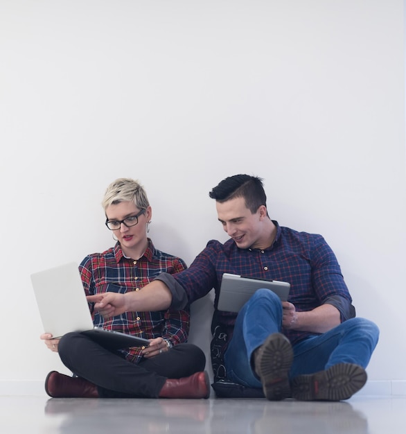 Foto negocio de inicio y nuevo concepto de tecnología móvil con una pareja joven en un interior de oficina moderno y luminoso que trabaja en una computadora portátil y una tableta en un nuevo proyecto creativo y lluvia de ideas