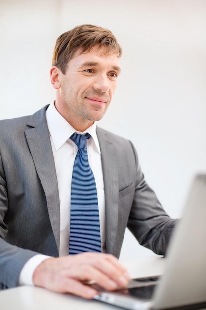 negocio, internet, tecnología y concepto de oficina - hombre de negocios sonriente con computadora portátil en la oficina