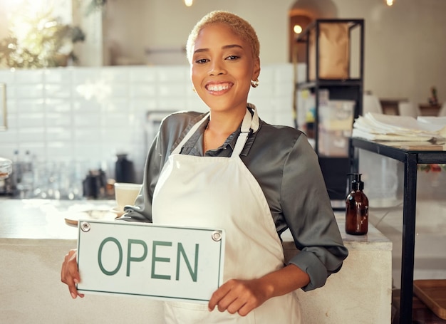 Negocio de letreros abiertos y retrato de mujer negra en un café restaurante o cafetería de inicio con una sonrisa para el éxito Gerente de camarera o persona que sostiene el tablero para servicios de bienvenida y carrera feliz