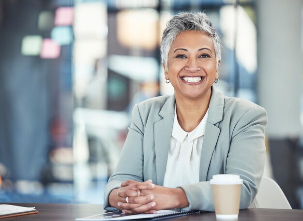 Foto negocio listo y retrato de una mujer en la empresa para el éxito y los objetivos de trabajo sonrisa feliz y madura empleada de oficina sentada en un escritorio para comenzar a trabajar por la mañana en una empresa legal