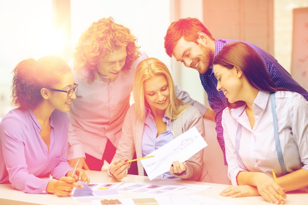 negocio, oficina, diseño de ropa y concepto de puesta en marcha - equipo creativo sonriente mirando boceto