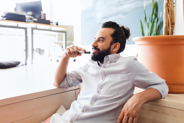 negocio, puesta en marcha, inspiración y concepto de personas - hombre latino feliz con barba y moño de pelo en la oficina