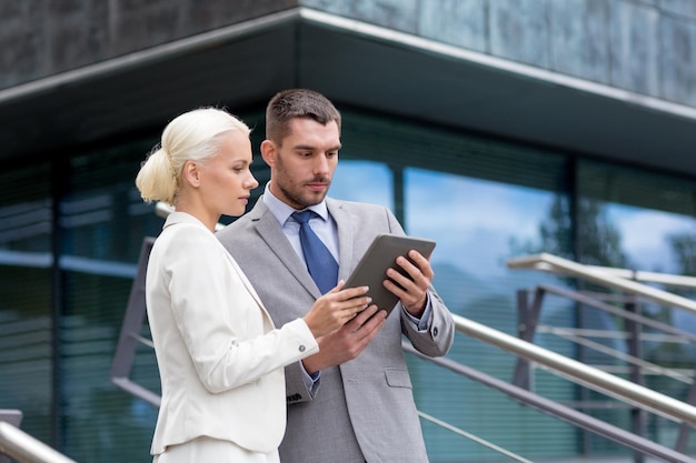 negocio, sociedad, tecnología y concepto de personas - hombre de negocios y mujer de negocios que trabajan con una computadora de tablet pc en la calle de la ciudad