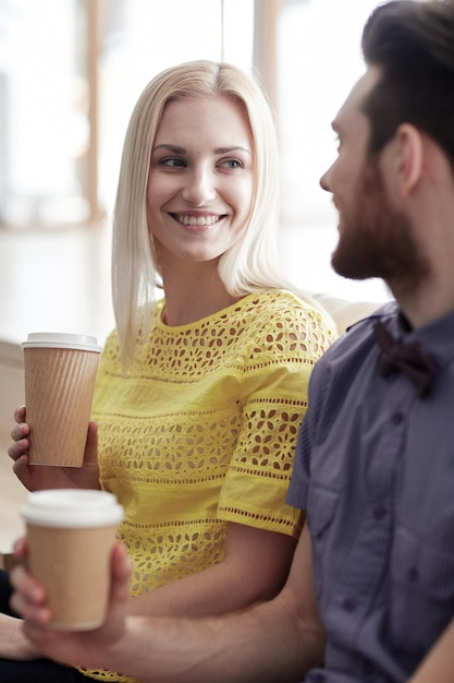 negocio, startup, personas y concepto de comunicación - hombre y mujer felices bebiendo café y hablando en la oficina