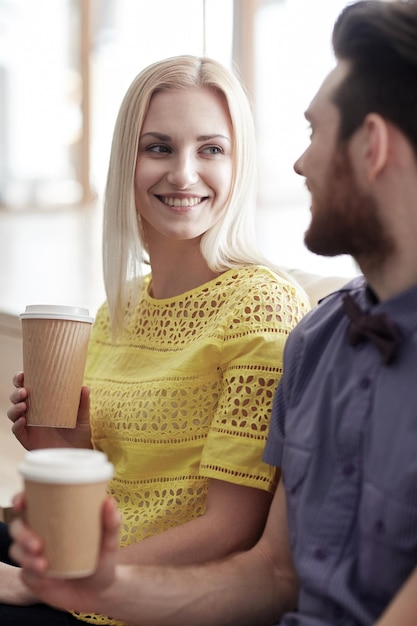 negócio, startup, pessoas e conceito de comunicação - homem e mulher felizes bebendo café e conversando no escritório