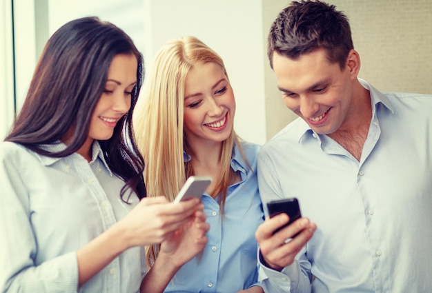 negocio, tecnología, internet y concepto de oficina - equipo de negocios sonriente con smartphones en la oficina