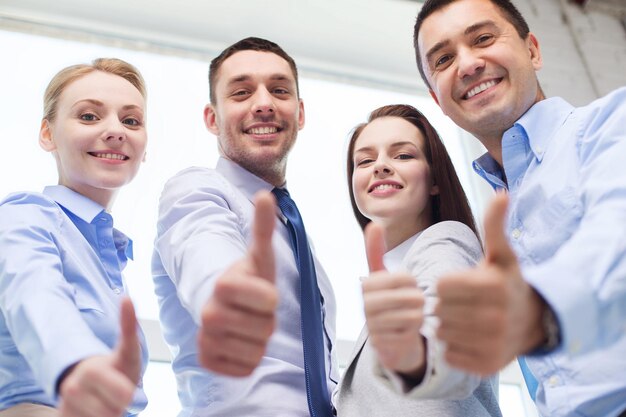 Foto negocio, trabajo en equipo, éxito, personas y concepto de gesto - equipo de negocios sonriente mostrando los pulgares hacia arriba en la oficina