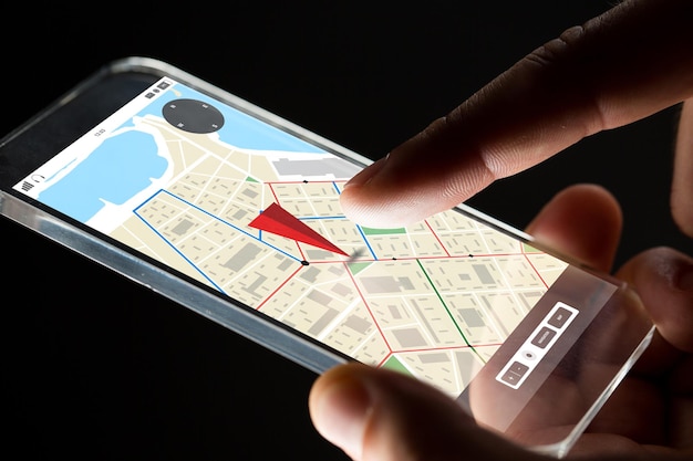 negocio, ubicación, personas y concepto de tecnología futura: cierre de la mano de un hombre de negocios con un teléfono inteligente transparente con un mapa del navegador gps en la pantalla sobre fondo negro