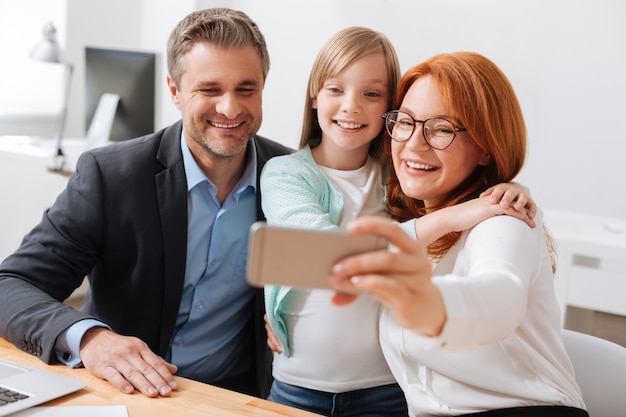 Foto negócios de família. criança alegre e sincera e seus pais relembrando um belo dia