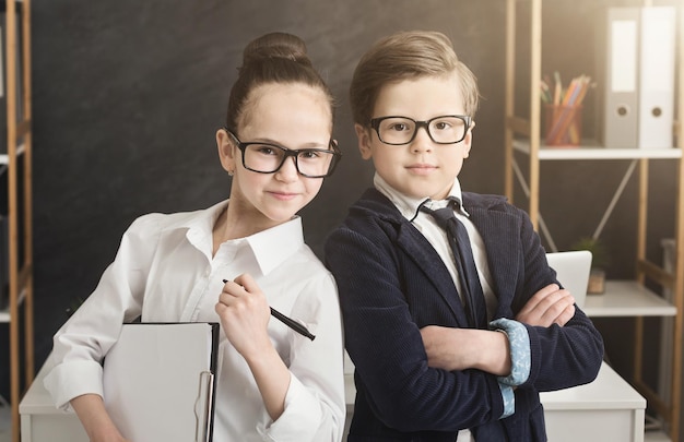 Negócios de família. Garoto bonito e garota com roupa formal, trabalhando juntos como uma equipe de sucesso, posando no escritório, copie o espaço