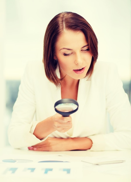 negocios, educación, concepto de personas - mujer de negocios o estudiante en anteojos trabajando con gráficos en la oficina