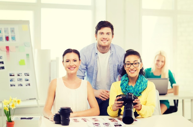 negocios, educación, fotografía, oficina y concepto de puesta en marcha - equipo creativo sonriente con cámara fotográfica trabajando en la oficina