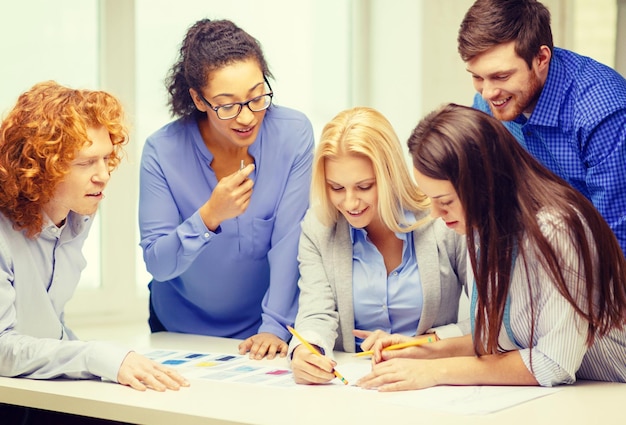 negócios, escritório, design de roupas e conceito de starup - equipe criativa sorridente, olhando os designs de roupas