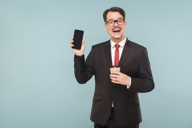 Negocios, gadgets, tecnologías. Hombre mostrando teléfono nuevo. Interior, foto de estudio, aislado sobre fondo azul claro o gris