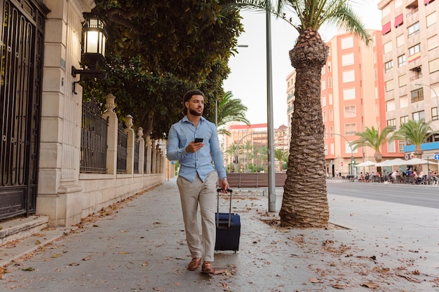 Negócios latino-americanos descem a rua com uma mala e um telefone celular