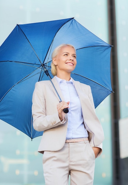 negocios, mal tiempo y gente y concepto - joven mujer de negocios sonriente con paraguas al aire libre