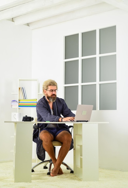 Negócios online Homem hipster cabelo despenteado rosto sem barba usando laptop Solidão falta interação humana Videoconferência online Cara de roupão descansando em casa Trabalho remoto Comunicação online