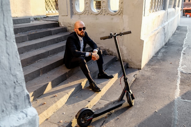 Negocios y personas y concepto. joven empresario montando scooter eléctrico al aire libre