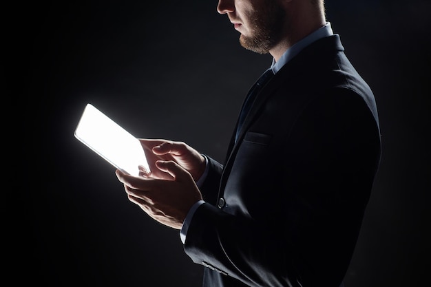 negocios, personas y concepto de tecnología futura: cierre de un hombre de negocios con una computadora de tableta transparente sobre negro