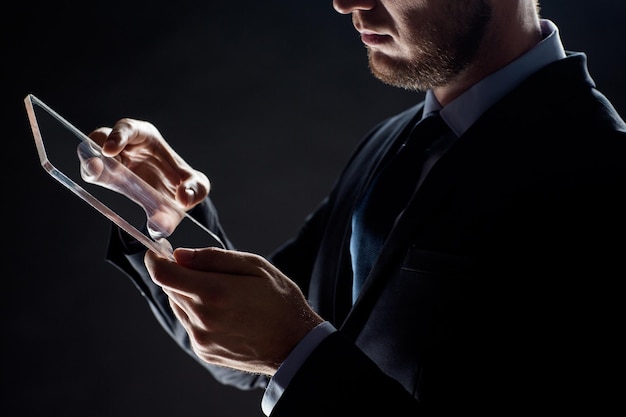 negocios, personas y concepto de tecnología futura - primer plano de un hombre de negocios con una tableta transparente sobre una computadora PC negra