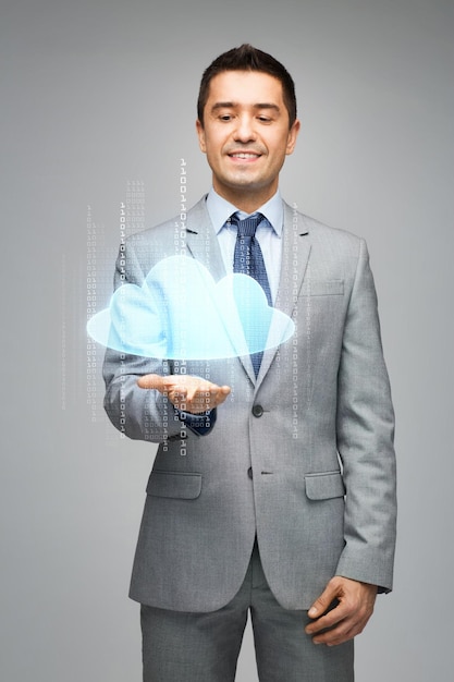 negocios, personas, tecnología y concepto de computación - hombre de negocios feliz en traje que muestra o sostiene una proyección de nube virtual en la palma sobre fondo gris