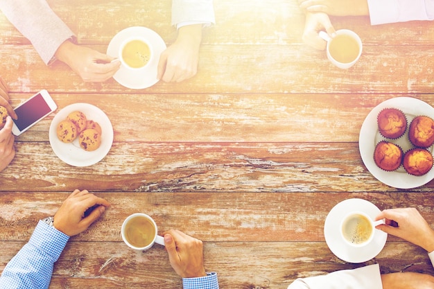 negócios, pessoas e conceito de trabalho em equipe - close-up da reunião de equipe criativa e tomando café durante o almoço no escritório