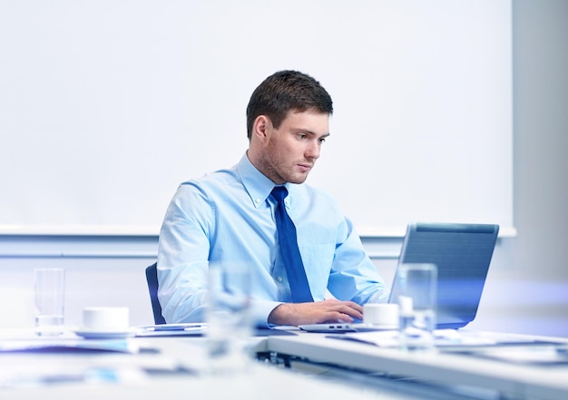 negócios, pessoas e conceito de trabalho - empresário com computador portátil sentado no escritório em frente ao quadro branco