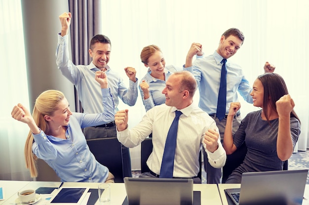 negócios, pessoas, tecnologia, gesto e conceito de trabalho em equipe - equipe de negócios sorridente levantando as mãos e comemorando a vitória no escritório