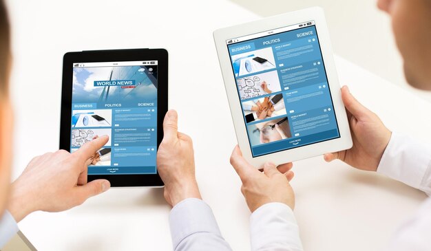 negócios, pessoas, tecnologia, internet e conceito de mídia - close-up das mãos do empresário com página da web de notícias em telas de computador tablet pc no escritório