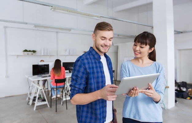 negocios, tecnología, personas y concepto - equipo creativo sonriente con smartphone y tablet pc en la oficina