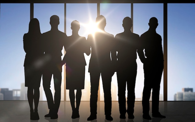 negocios, trabajo en equipo y concepto de personas - siluetas de personas de negocios sobre el fondo de la oficina